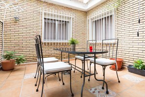 A patio with a brick wall, a metal table, and two chairs. - Rafaela Guest House (Málaga)