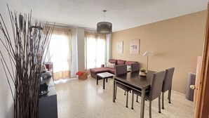 A living room with a sofa, dining table, chairs, and a decorative vase. - Rafaela Guest House (Málaga)