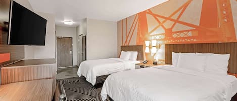 A hotel room with two beds, a TV, and a large wall mural.