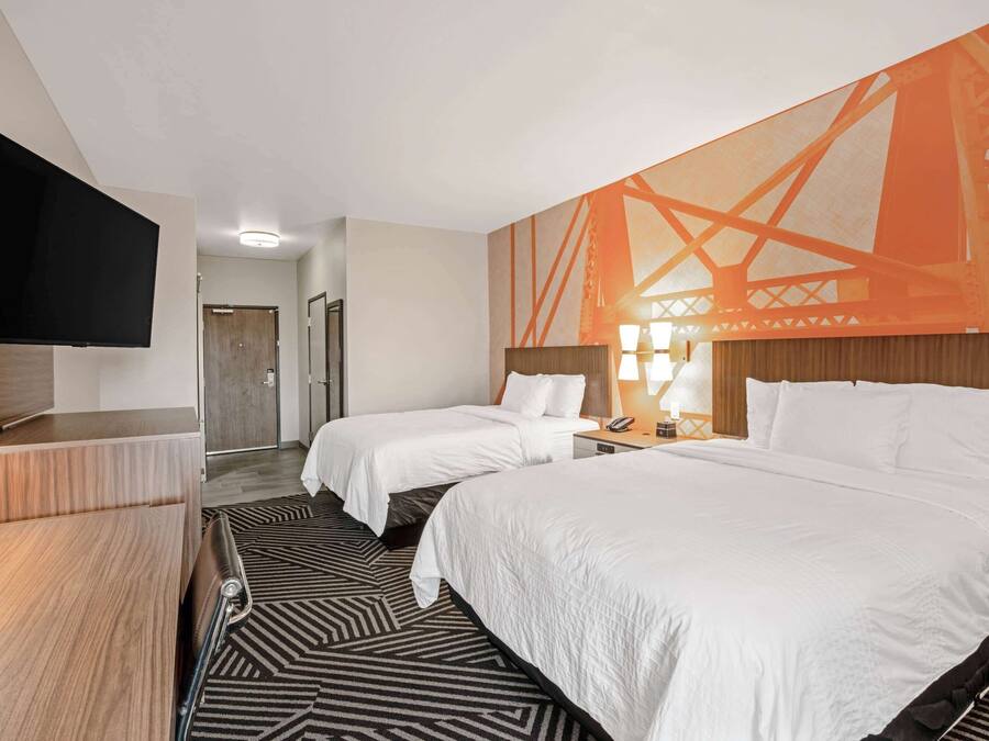 Una habitación de hotel con dos camas, un televisor y un mural grande en la pared.
