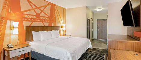 Habitación de hotel con cama, mesitas de noche con lámparas, un televisor y una alfombra estampada.