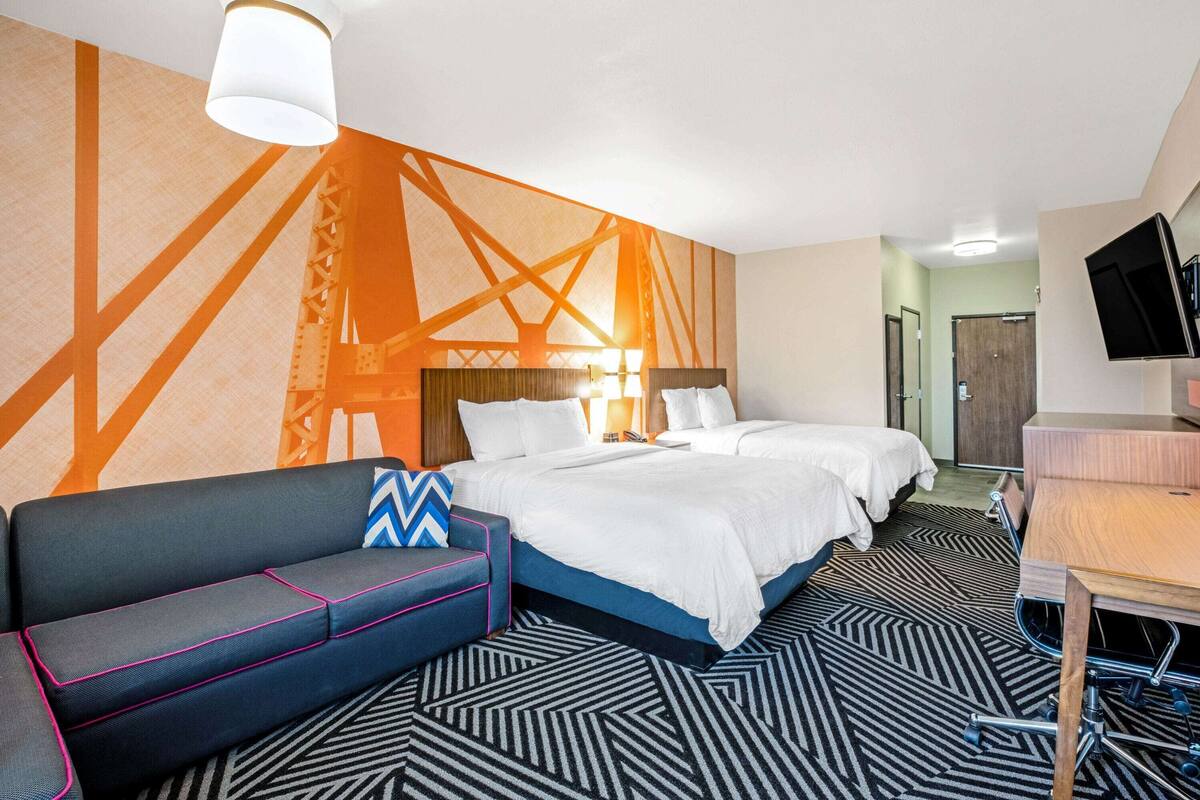A hotel room with a bed, two bedside tables, a sofa, a desk, and a TV.