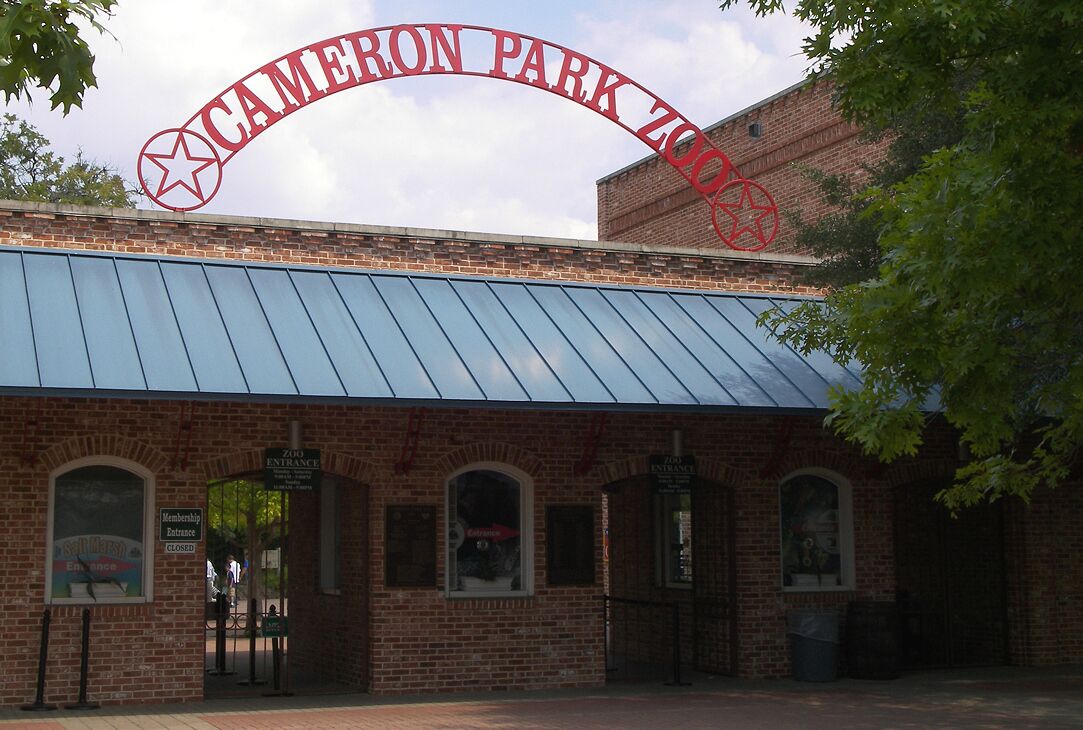 A brick building with a blue roof and a sign reading "CAMERON PARK ZOO".