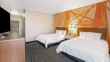 A hotel room with two beds, a TV, and a large mural on the wall.
