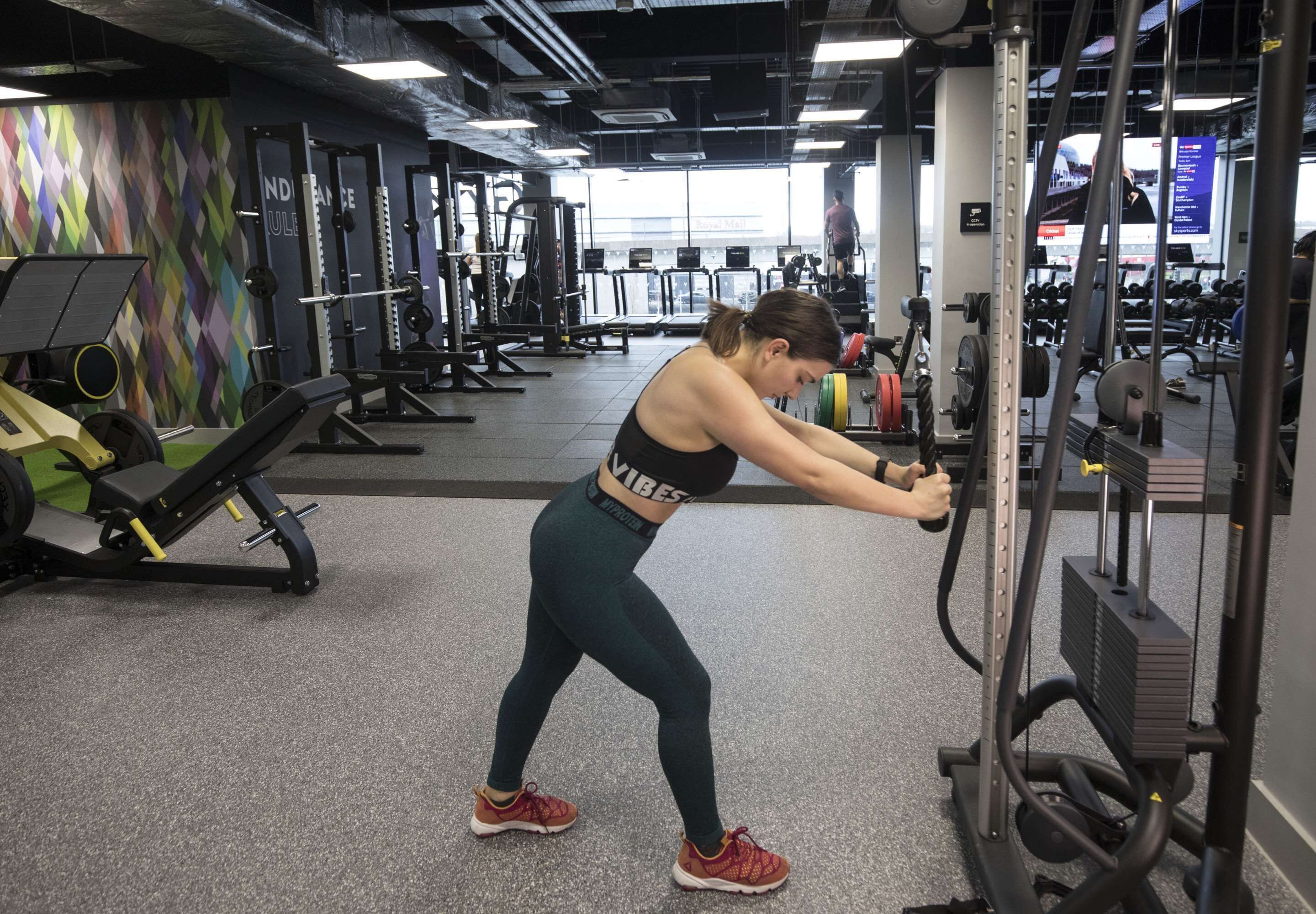 Ein Fitnessraum mit verschiedenen Trainingsgeräten, darunter ein Kabelzug und Gewichtshalterungen.