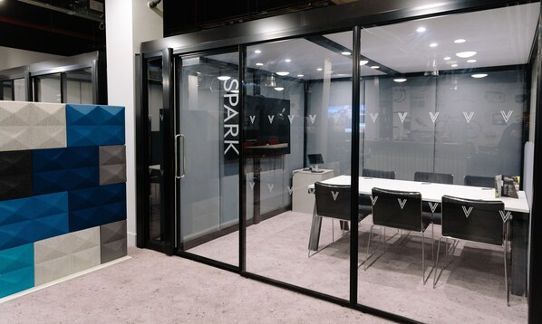 A modern conference room with a glass door labeled "SPARK," a white table, and black chairs. - Village Hotel Bristol (Bristol)