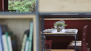Una mesa de comedor dispuesta con vasos y un jarrón de flores, rodeada de sillas.