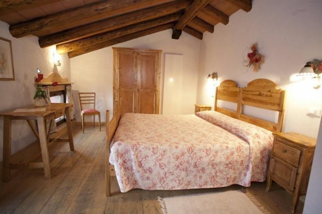 A bedroom with a wooden bed, a wooden desk, a chair, and a wardrobe.