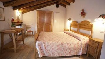 A bedroom with a wooden bed, a wooden desk, a chair, and a wardrobe.