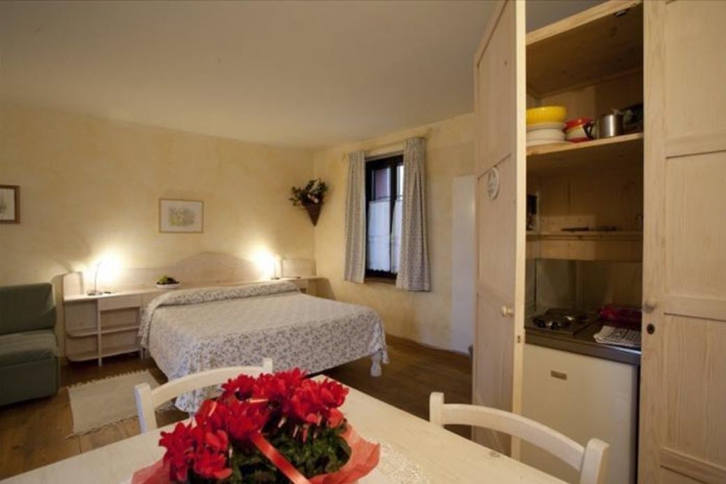 A bedroom with a bed, bedside table, and a small table with a bouquet of flowers.