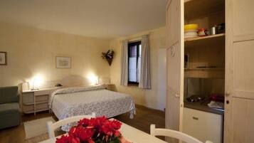 A bedroom with a bed, bedside table, and a small table with a bouquet of flowers.