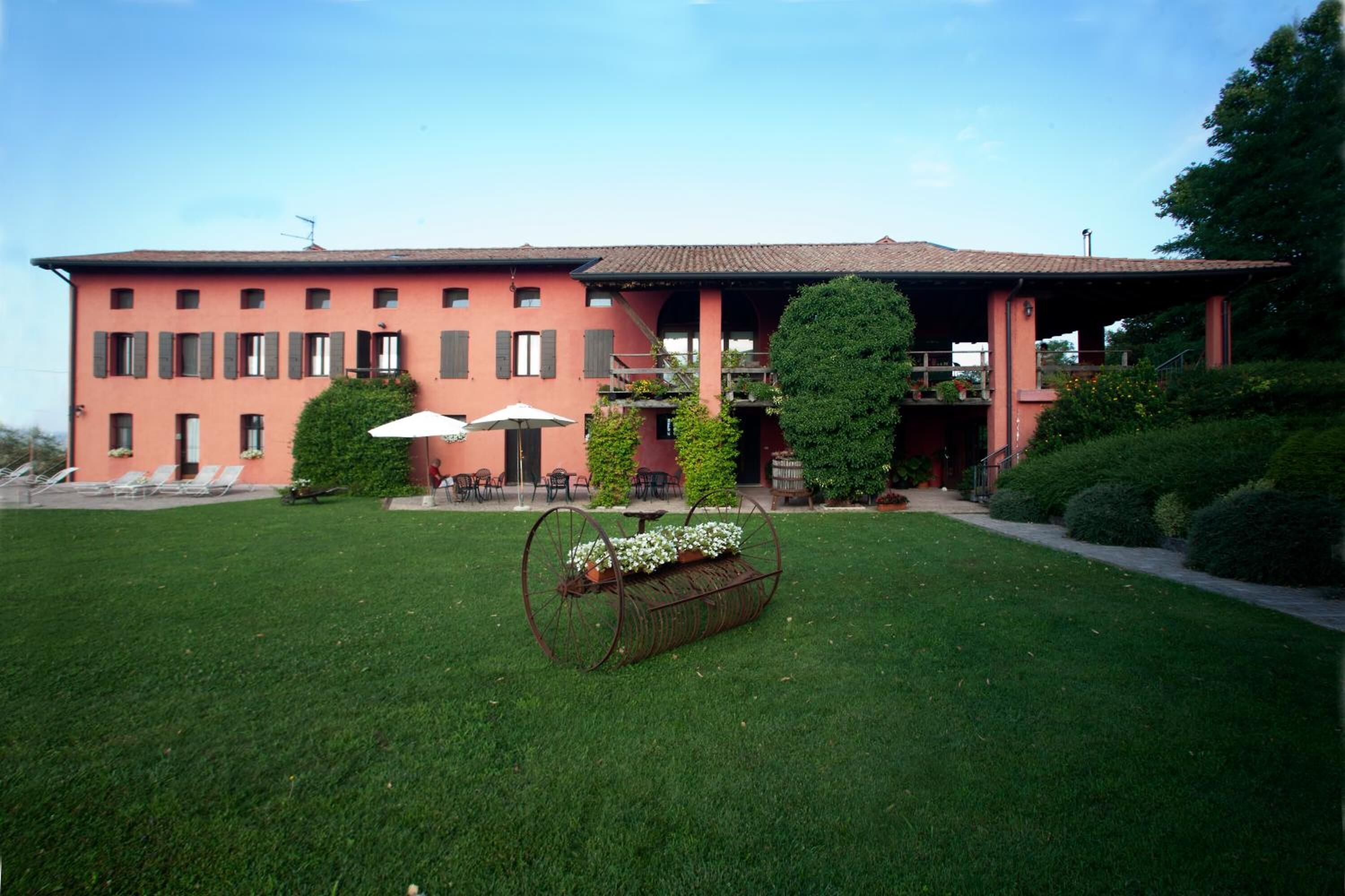 Un edificio imponente con facciata rossa, una veranda coperta con posti a sedere all'aperto e un prato curato.