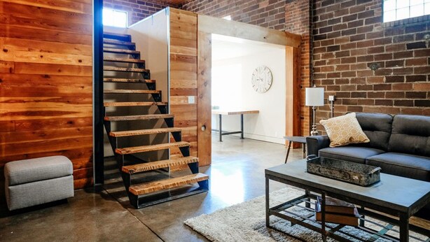 A modern interior with a wooden staircase, a leather sofa, and a dining area. - The Nelson Inn (Sheridan)