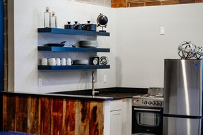 A kitchen with a wooden countertop, a stove, an oven, and a stainless steel refrigerator.