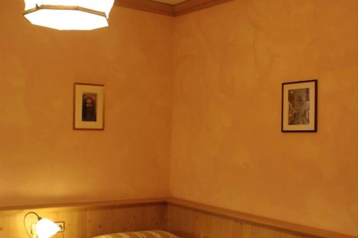 Ein Einzelbett mit gestreifter Decke, ein Nachttisch mit Lampe und ein kleiner runder Tisch.