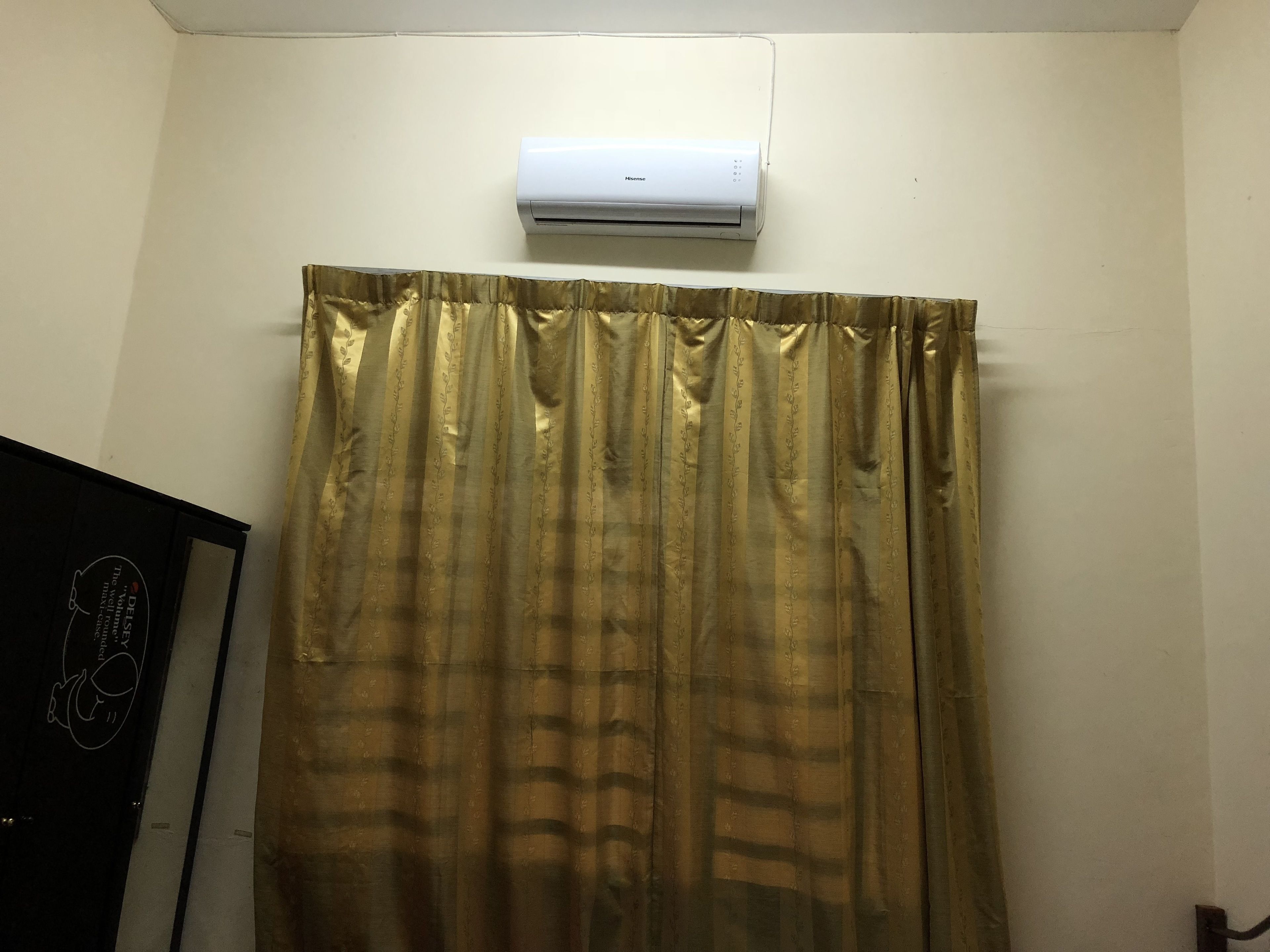 Une salle de bain avec un appareil de climatisation blanc fixé au mur, au-dessus du rideau de douche.