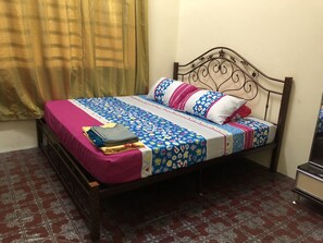 Een bed met een laken met dessin, kussens en opgevouwen dekens.