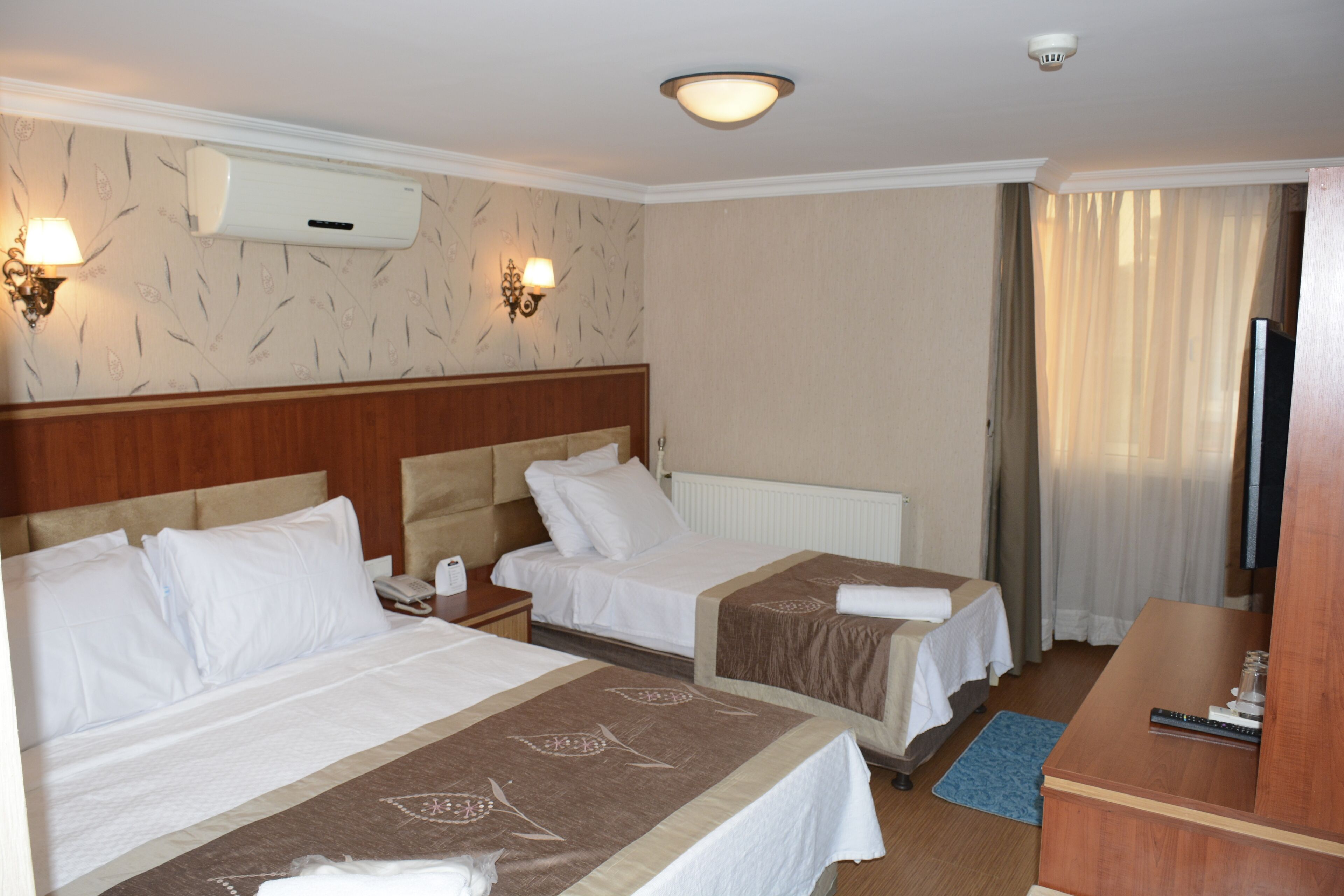 A hotel room with two beds, a TV, and a desk.