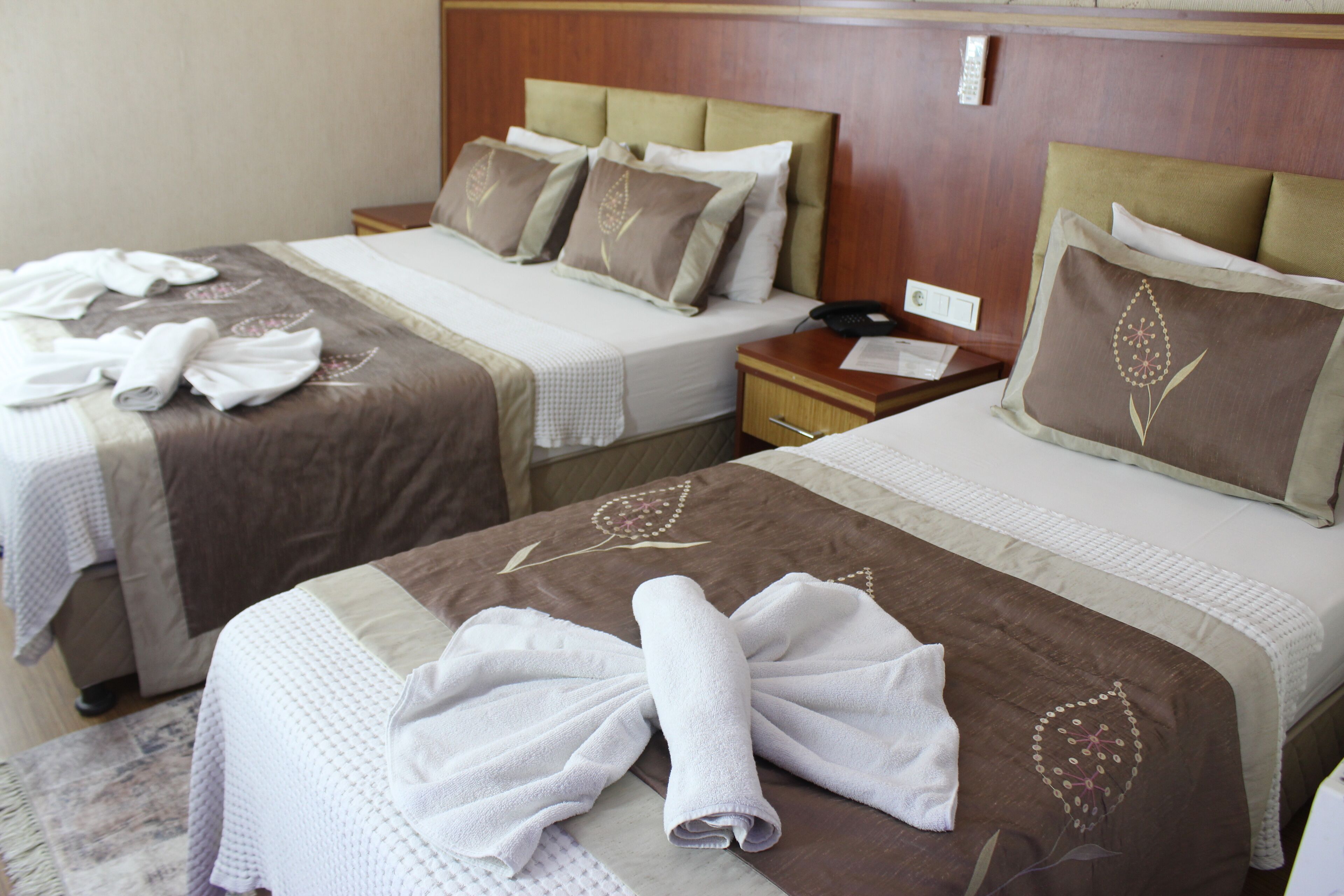 Two hotel beds with towels, a nightstand, and a wall-mounted phone.