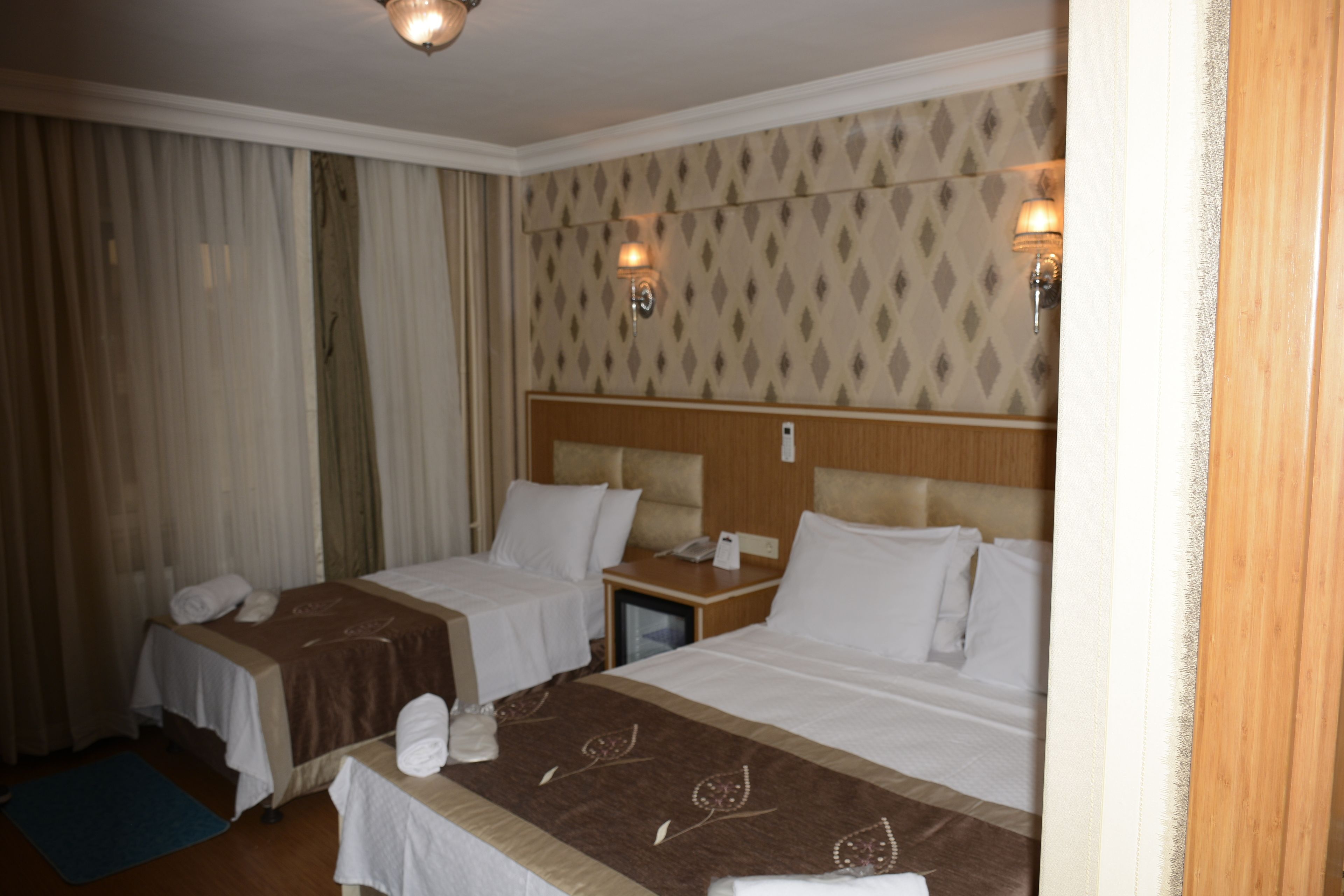 Ett hotellrum med två sängar, ett nattduksbord och ett skrivbord med en lampa.