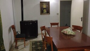 A dining area with a wooden table, six chairs, a painting on the wall, and a closed door. - Wardini (Bhamdoun)
