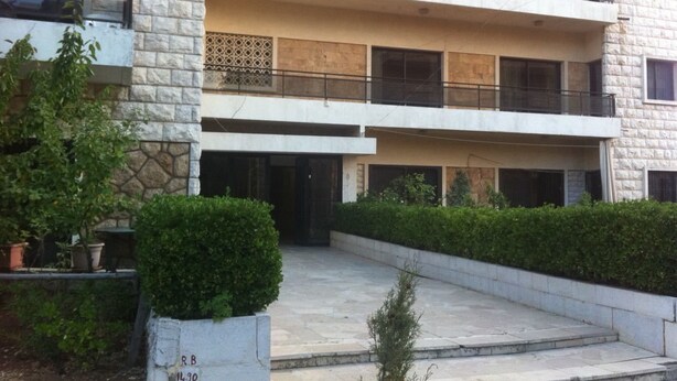 A multi-story building with a stone facade, balconies, and a gated entrance. - Wardini (Bhamdoun)