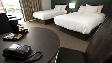 Une chambre d’hôtel avec deux lits, un bureau avec un téléphone et une vue sur l’extérieur.