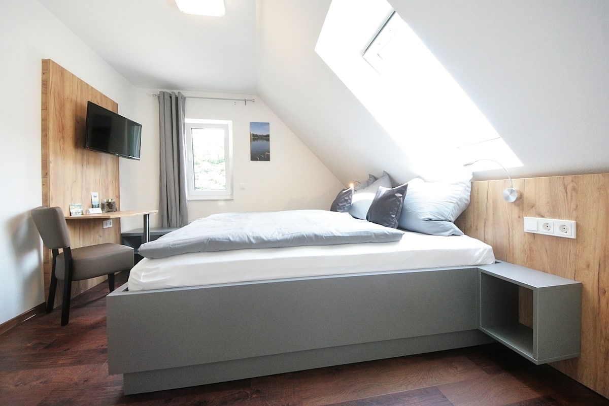 Un dormitorio moderno con cama empotrada, escritorio y televisor montado en la pared.