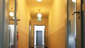 Un pasillo con suelo de madera, puertas de cristal y luces en el techo.