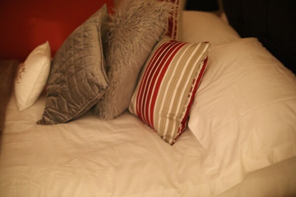 Una cama con varios almohadones de distintas texturas y diseños.