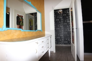 Een badkamer met een wit wastafelmeubel, een spiegel met blauwe lijst en een muur met tekst over koffie.