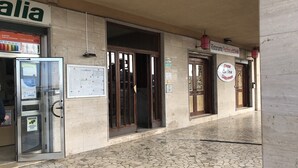 Entrada de un edificio con suelo de baldosas, puerta de cristal y letrero de restaurante.