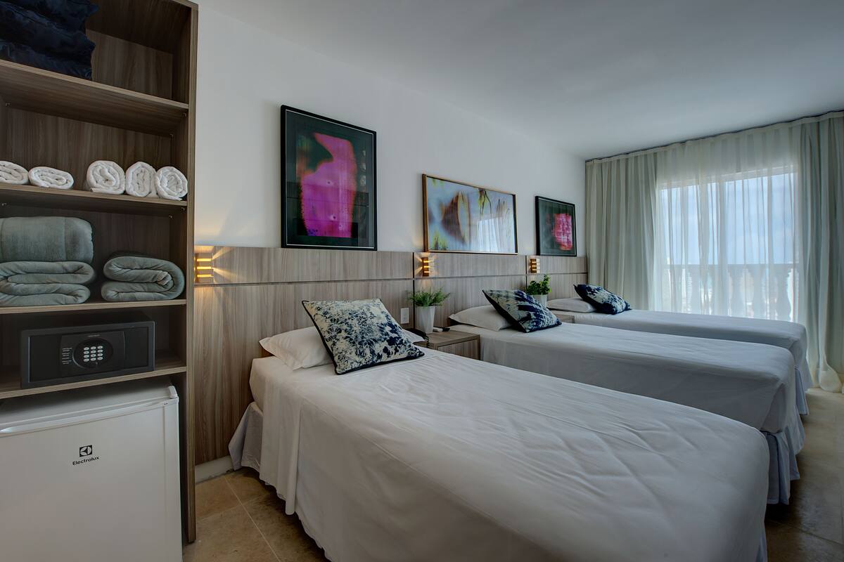 Ein Hotelzimmer mit zwei Betten, einer Minibar und Bildern an den Wänden.