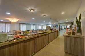 Un amplio vestíbulo de hotel con una larga recepción, varias zonas de estar y una lámpara moderna.