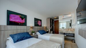 Habitació d'hotel amb dos llits, un bany amb un rentaplat i un mirall, i obres d'art a les parets.