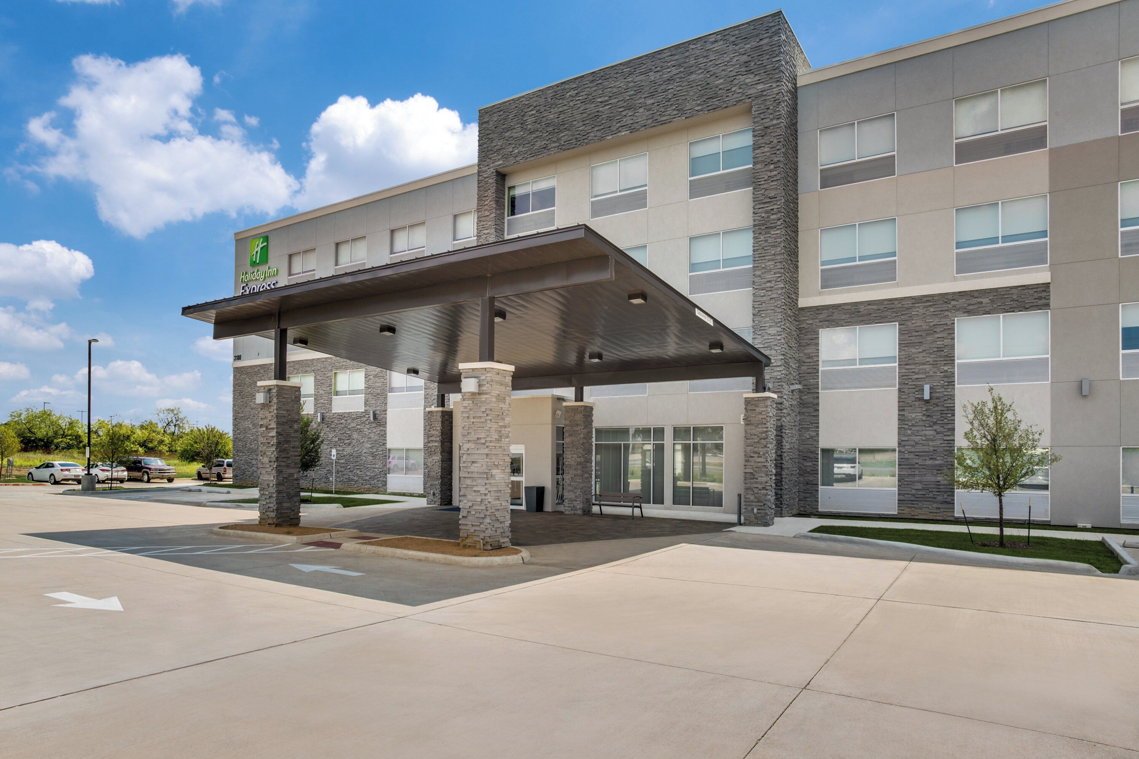A Holiday Inn Express building with a covered entrance, stone pillars, and a parking lot.