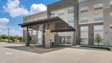 A Holiday Inn Express building with a covered entrance, stone pillars, and a parking lot.