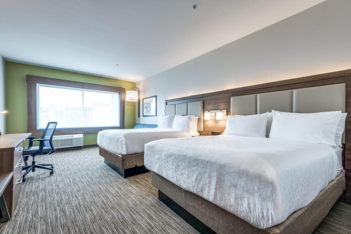 A hotel room with two beds, a desk, and a chair.