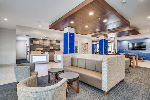 A modern lobby with a seating area, a reception desk, and a large screen. - Holiday Inn Express & Suites Denton South by IHG (Denton)