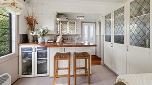 A kitchen with a wooden countertop, two stools, a sink, and cabinets. - Private seaside couples hideaway (Kaka Point)