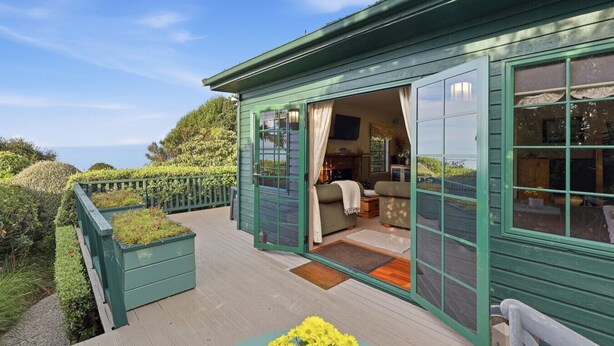 Una casa verde con una veranda, un interno accogliente con un divano e un televisore.