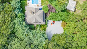 Vue aérienne d’une propriété dotée d’une piscine entourée de chaises longues et de parasols, d’un patio couvert et d’un petit bâtiment.