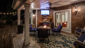 Une terrasse extérieure dotée d’un foyer, de sièges et d’un téléviseur.