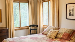 A bedroom with a large bed, two windows with curtains, a chair, a dresser, and a framed picture on the wall. - Chesapeake on Parker Lake (Oxford)