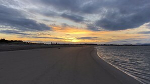 A beach with a curved shoreline and a sunset in the background.