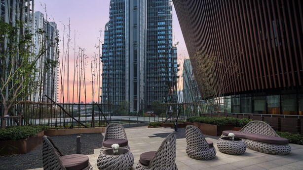 A rooftop terrace with wicker furniture and a view of tall buildings. - Holiday Inn Nanjing South Station by IHG (Nanjing)