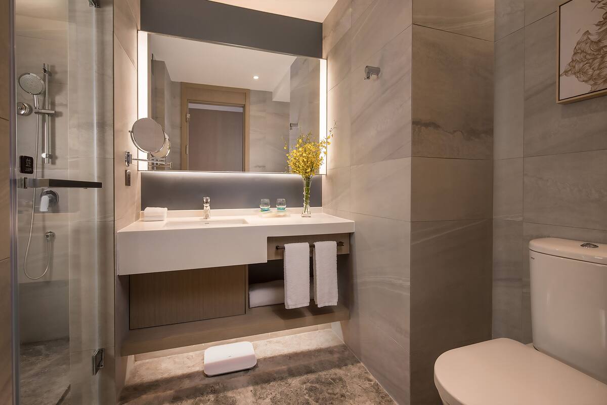A modern bathroom with a glass-enclosed shower, a white sink with a mirror, and a toilet.