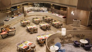 A modern hotel lobby with a curved reception desk, multiple seating areas, and a bar with a variety of food and drink options. - Holiday Inn Nanjing South Station by IHG (Nanjing)