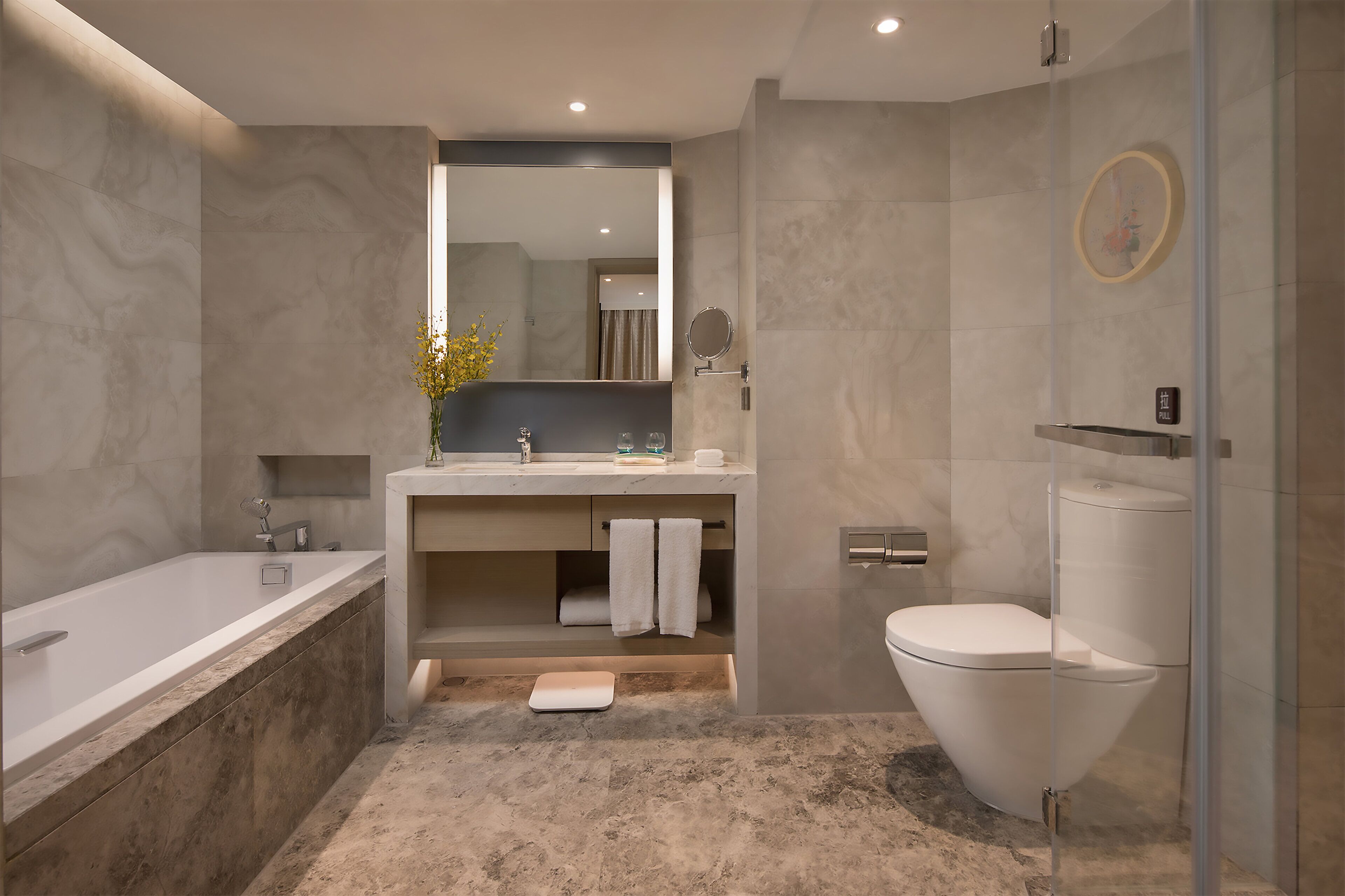 Een moderne badkamer met een bad, toilet en douche.
