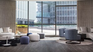 A modern hotel lobby with a large window offering a view of a cityscape. There are sofas, ottomans, and a coffee table. - Holiday Inn Nanjing South Station by IHG (Nanjing)